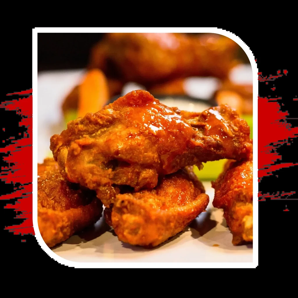Crispy chicken wings with orange-red sauce on a black background.