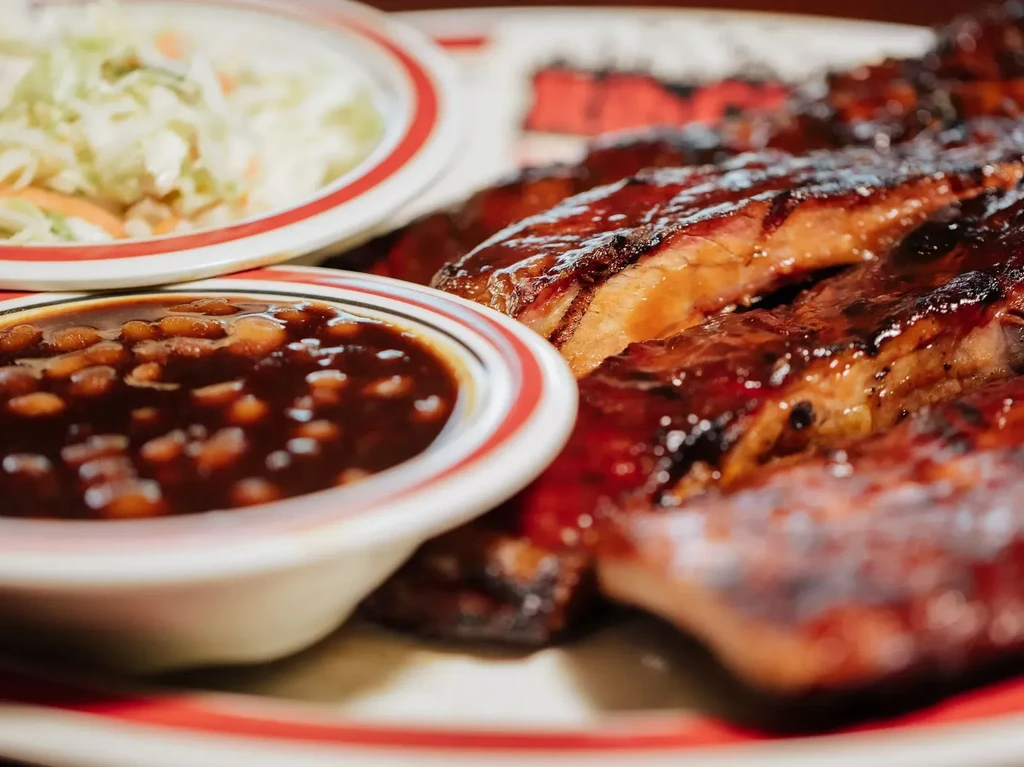 Barbecue ribs, baked beans, and coleslaw on a casual diner plate.