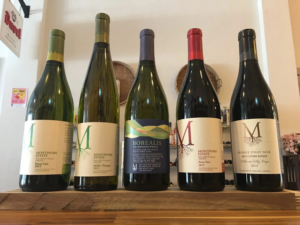 Five distinct wine bottles with varied, detailed labels on wood.
