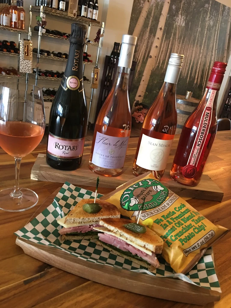 Sparkling and still rosé wines, sandwich, and chips in a wine bar.