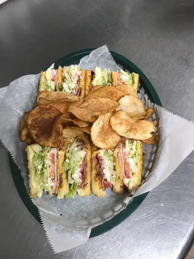 Club sandwiches revealing layers of meat, cheese, lettuce, and potato chips.