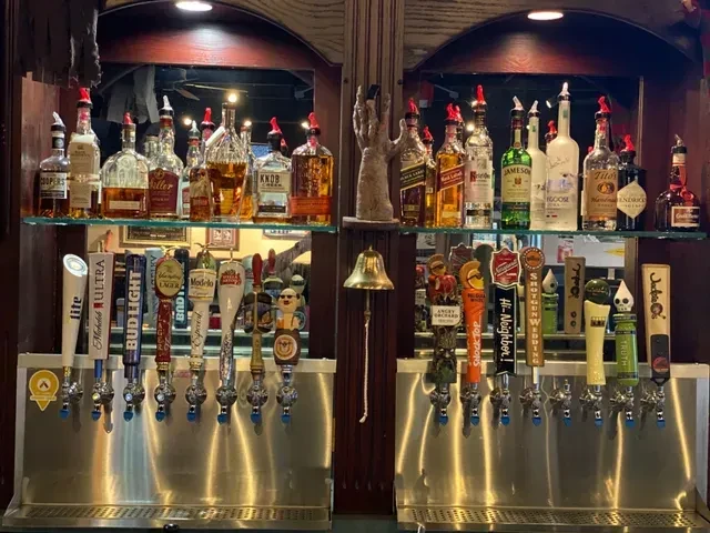 Well-stocked bar with liquor bottles and branded draft beer taps.