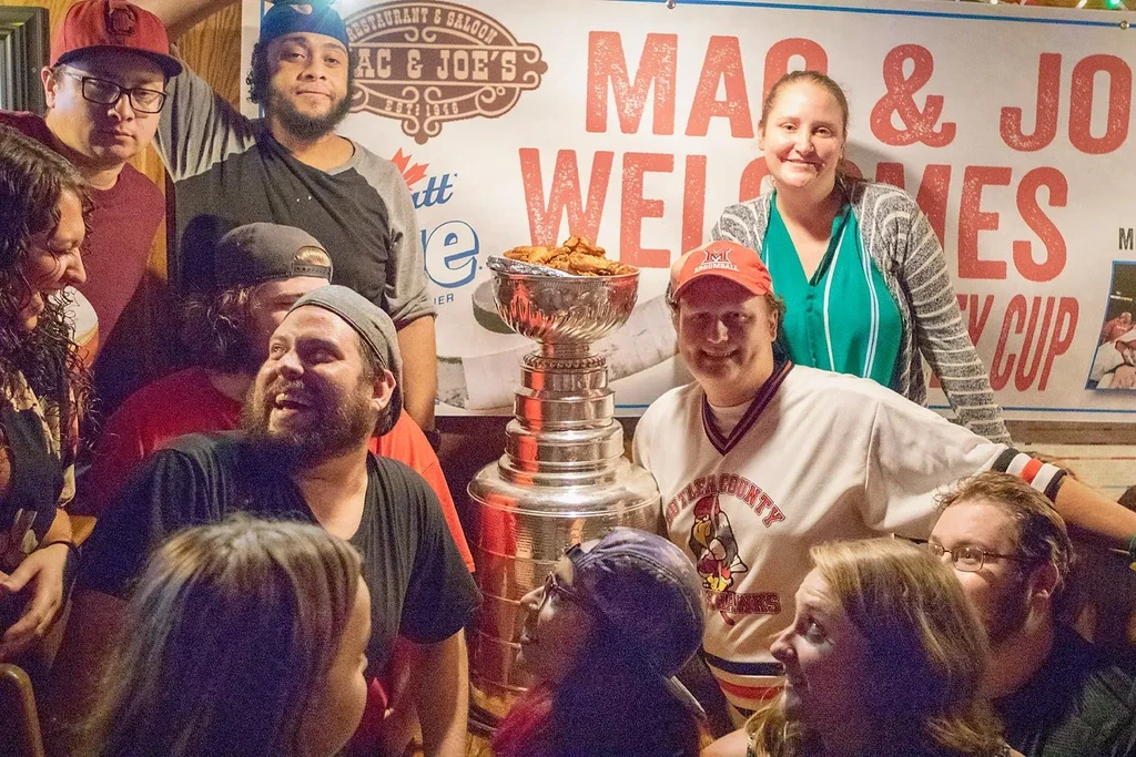 Smiling group gathered around a trophy overflowing with fried chicken wings.