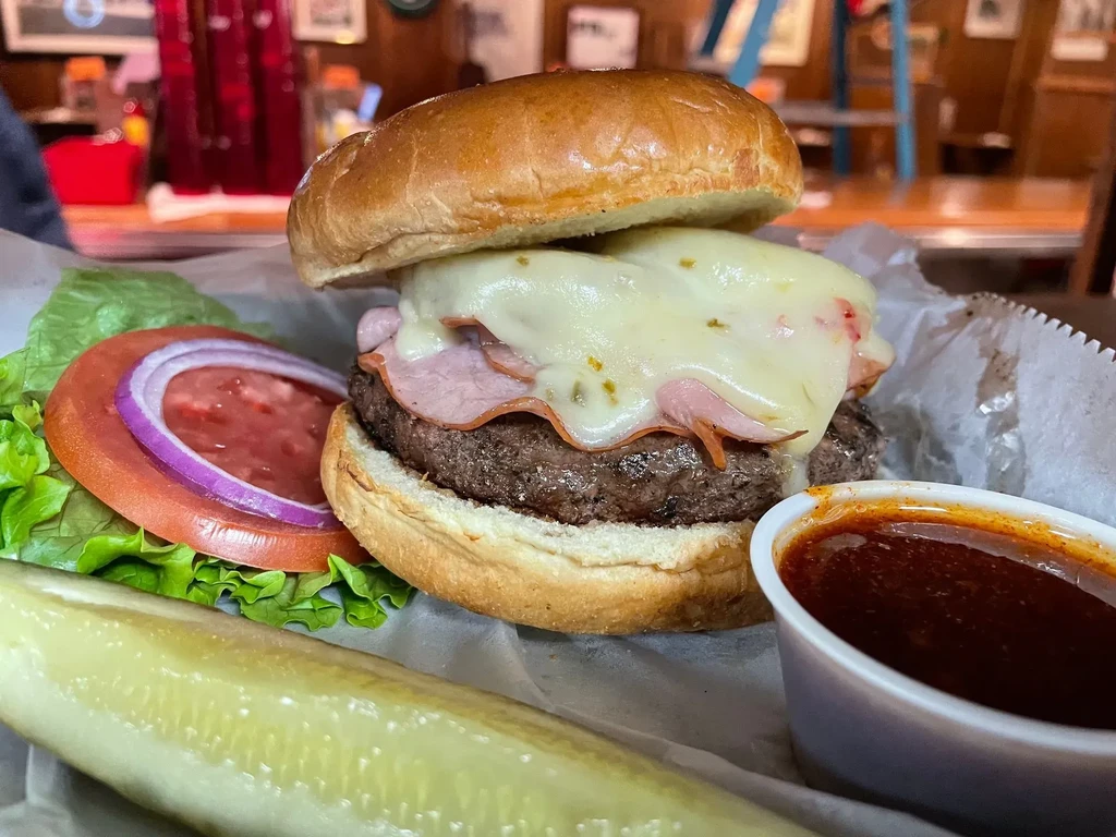 Substantial gourmet burger, ham, melted cheese, pickle, and dipping sauce.