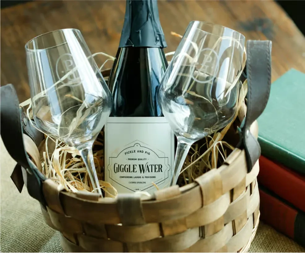 Gift basket with "Giggle Water" sparkling wine and two monogrammed wine glasses.