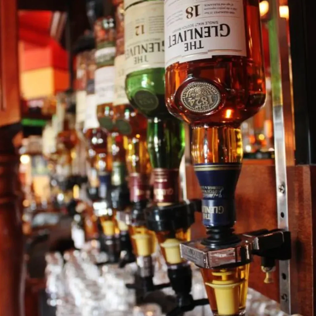 Inverted THE GLENLIVET 18-year scotch and other bottles in bar pourers.