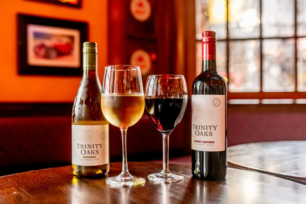 Bottles of Trinity Oaks Chardonnay and Cabernet Sauvignon with glasses.