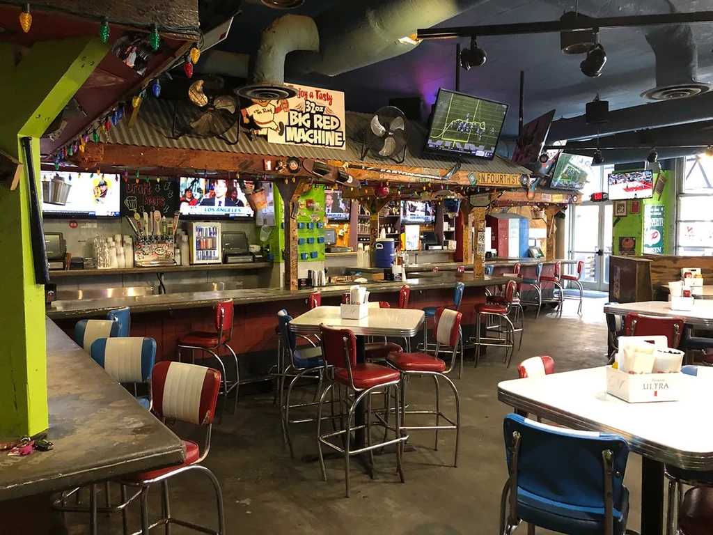Empty retro sports bar interior with colorful lights and televisions.