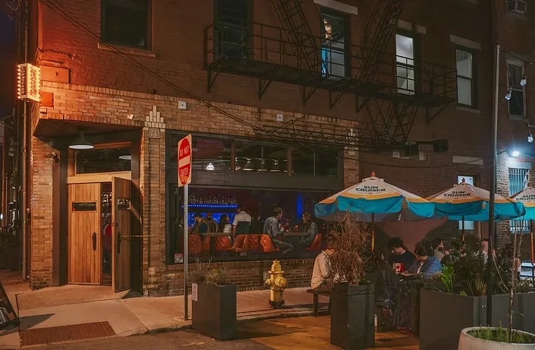 Nighttime brick building with bar, lively patio, 'SUN CRUISER' umbrellas.