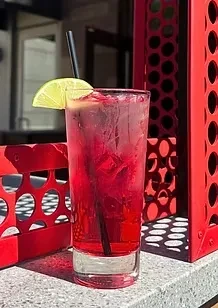 Pink drink with lime and ice in glass, red perforated screen.