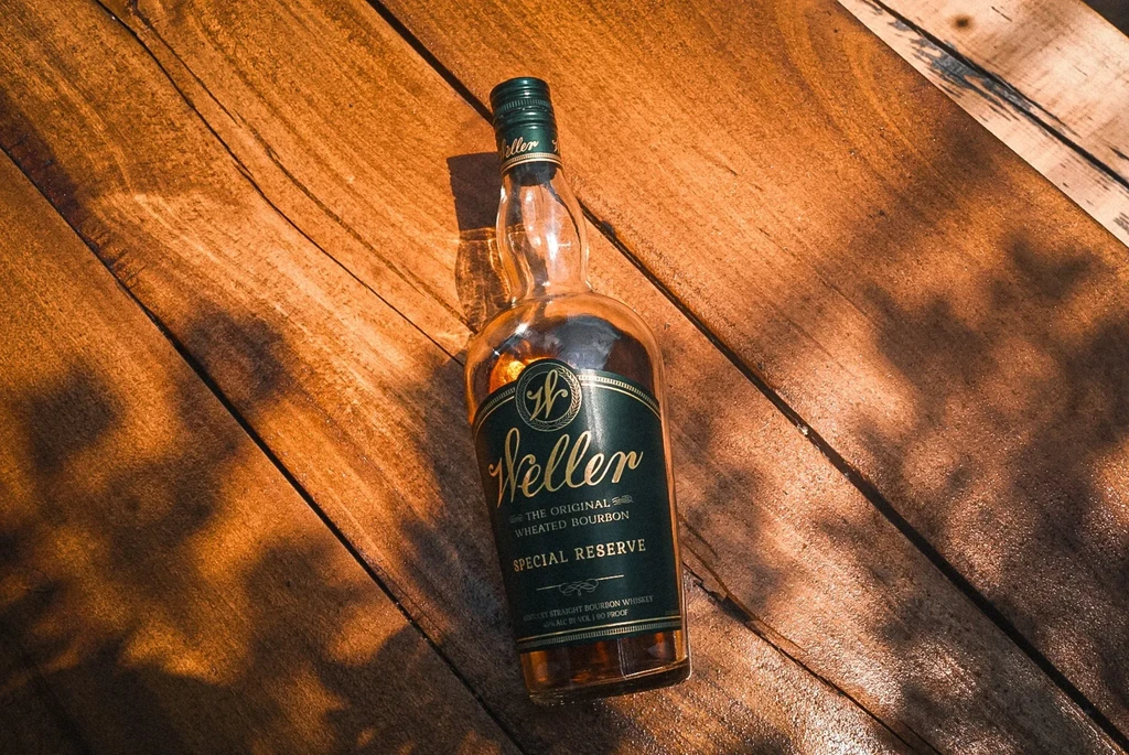 Weller bourbon bottle on rustic wooden surface with dramatic lighting.