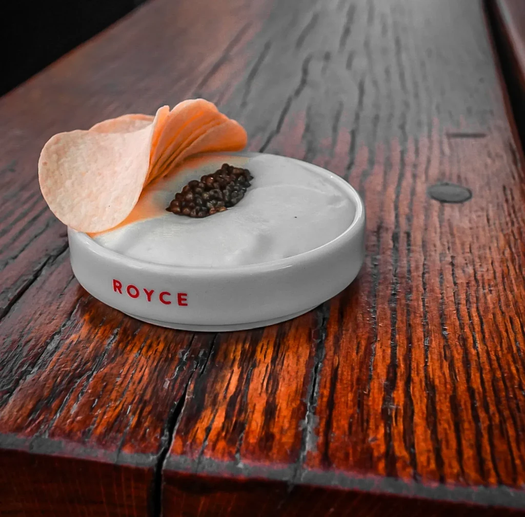 Close-up of 'ROYCE' dish with cream, caviar-like spheres, potato crisp.