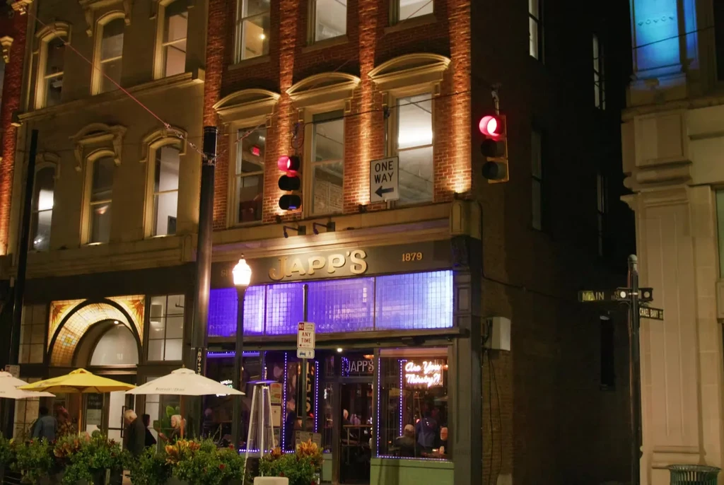 Night scene: JAPP'S 1879 bar, purple neon, and outdoor seating.