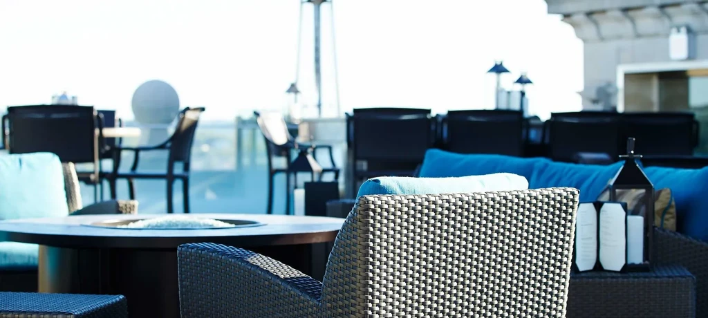 Bright rooftop lounge with fire pit table, chairs, and patio heater.