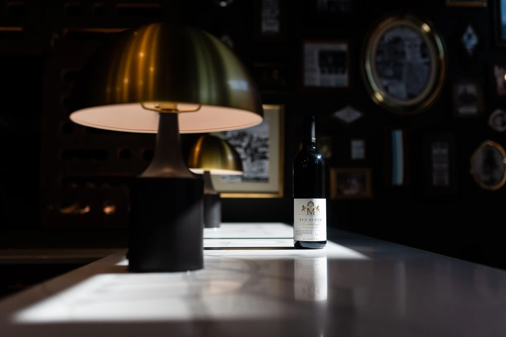 Golden mushroom lamp illuminates a dark wine bottle on a counter.