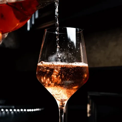 Close-up: Sparkling rosé pours into a clear wine glass.