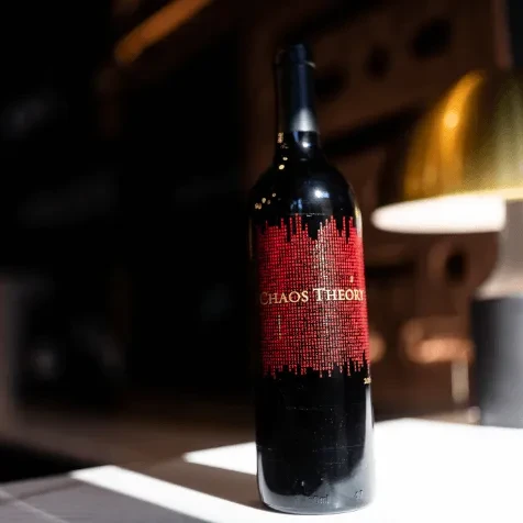 Dark wine bottle with red pixelated "CHAOS THEORY" label, 2019 vintage.