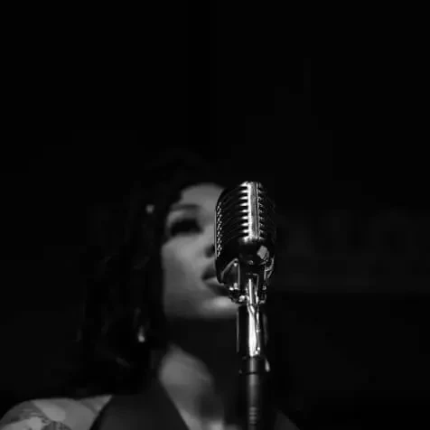 Moody black and white photo of a vintage microphone and blurred singer.