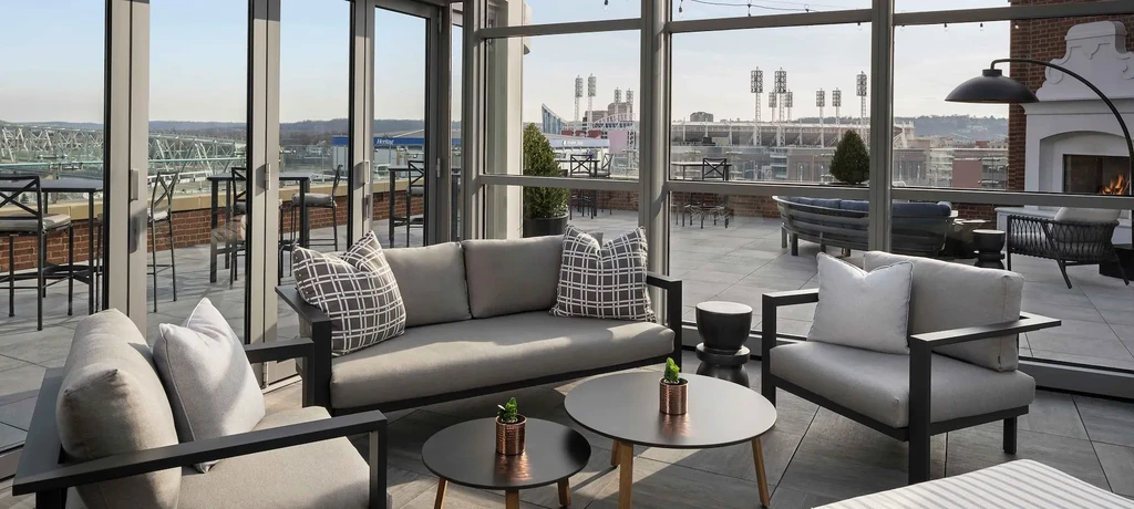 Rooftop lounge with indoor/outdoor seating and a city stadium view.