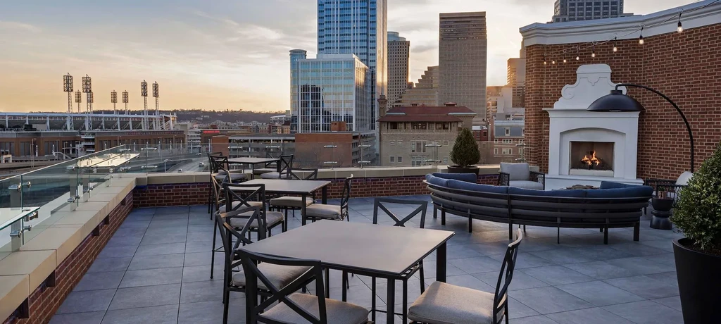 Rooftop patio with city view, outdoor seating, and fireplace at dusk.