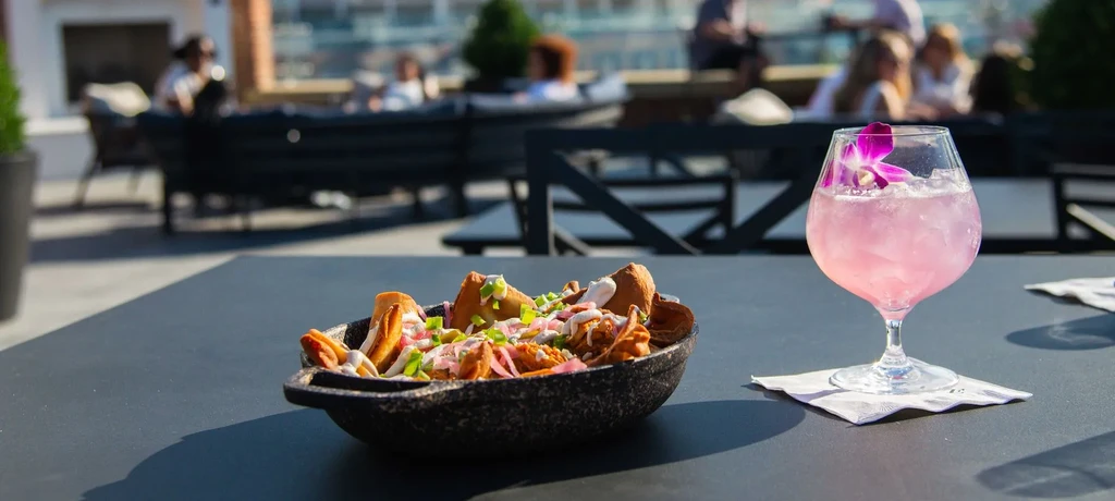 Rustic nachos and orchid-garnished pink cocktail on a bright patio.