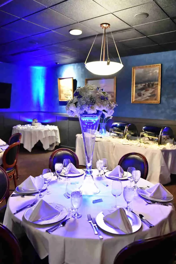 Blue-lit elegant restaurant interior with a beautifully set octagonal table.