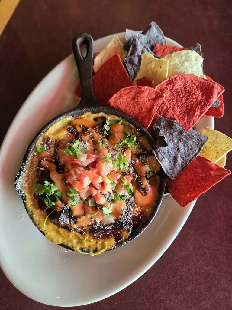 Creamy dip with tomatoes and herbs, in skillet with tortilla chips.