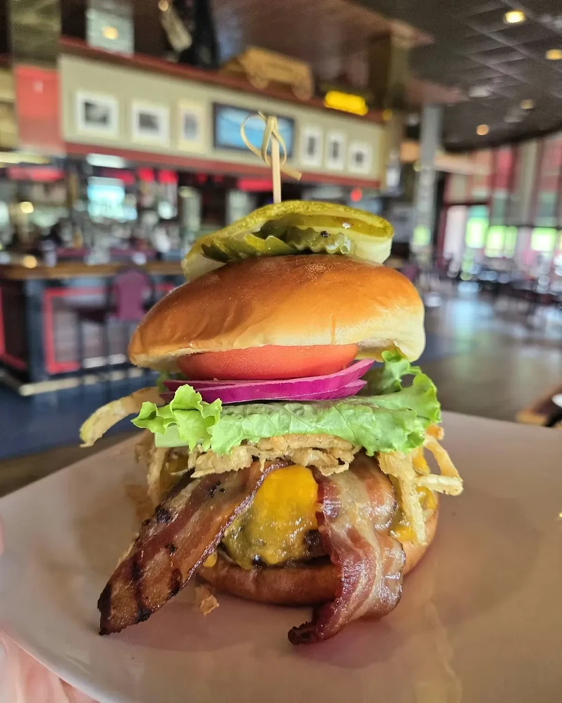 Close-up of a gourmet hamburger with bacon, cheese, and vegetables on a plate.