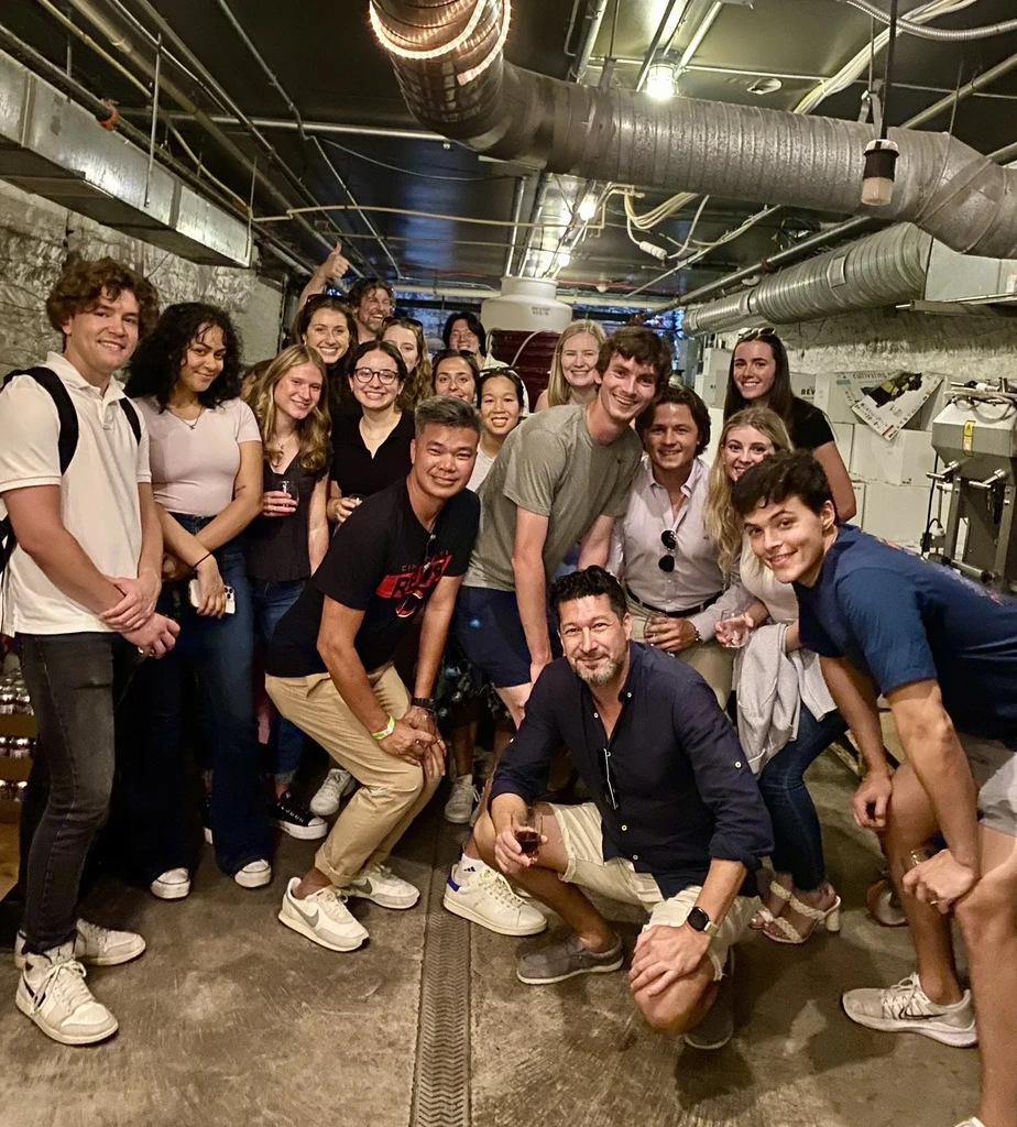 Smiling young adults holding glasses in an industrial winery setting.
