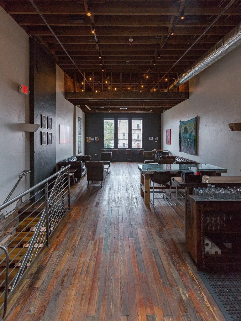 Industrial-chic restaurant interior with a bar, lounge, and wooden floor.