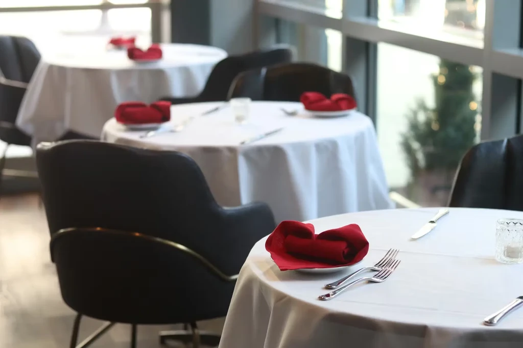 Elegant restaurant interior showing meticulously set tables with red napkins.