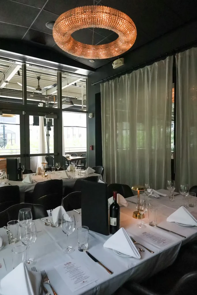 Modern upscale restaurant dining room with set tables and a crystal chandelier.