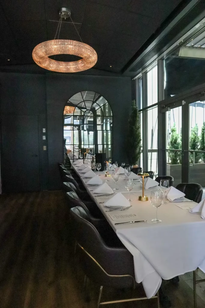 Long set table with crystal chandelier in an elegant, empty restaurant.