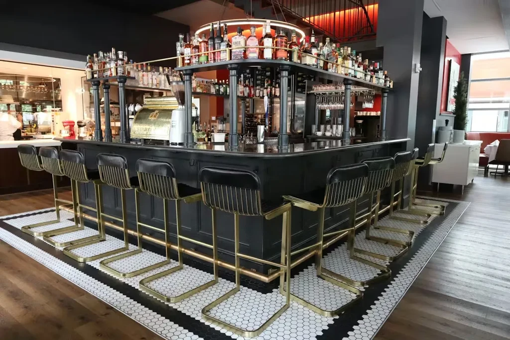 Modern bar with dark counter, tiered bottle rack, and gold-frame stools.