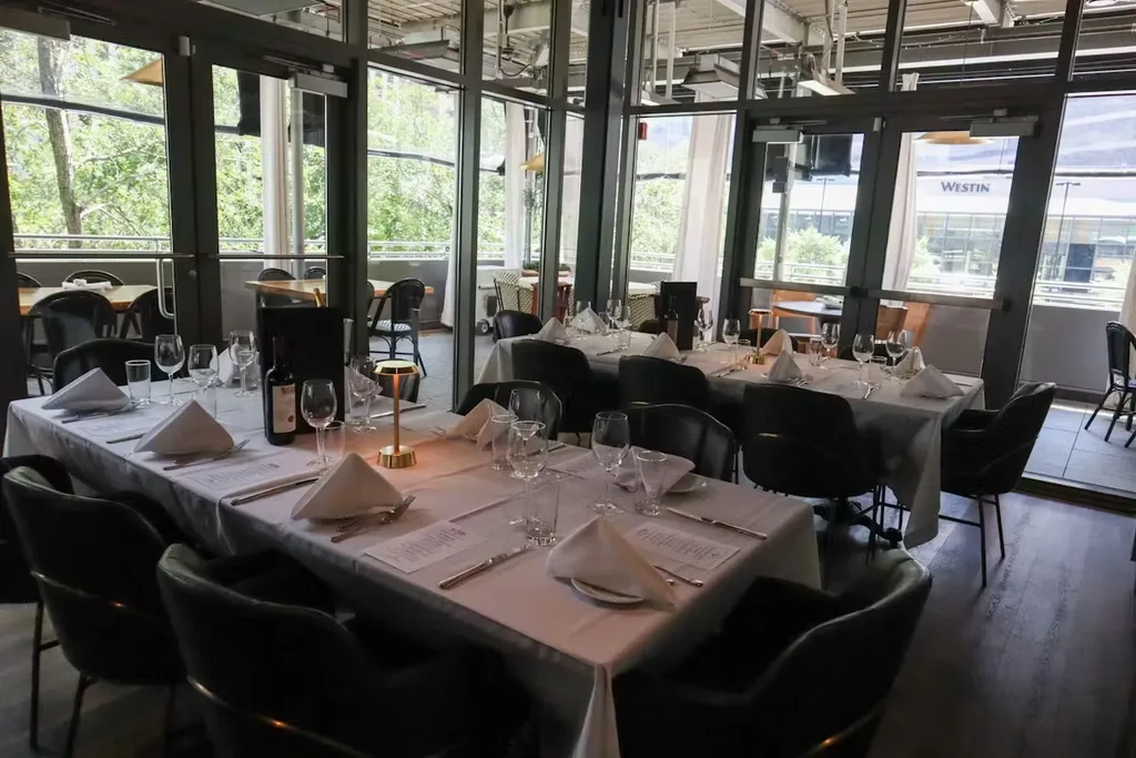Upscale restaurant interior with set tables, large windows, and a patio view.