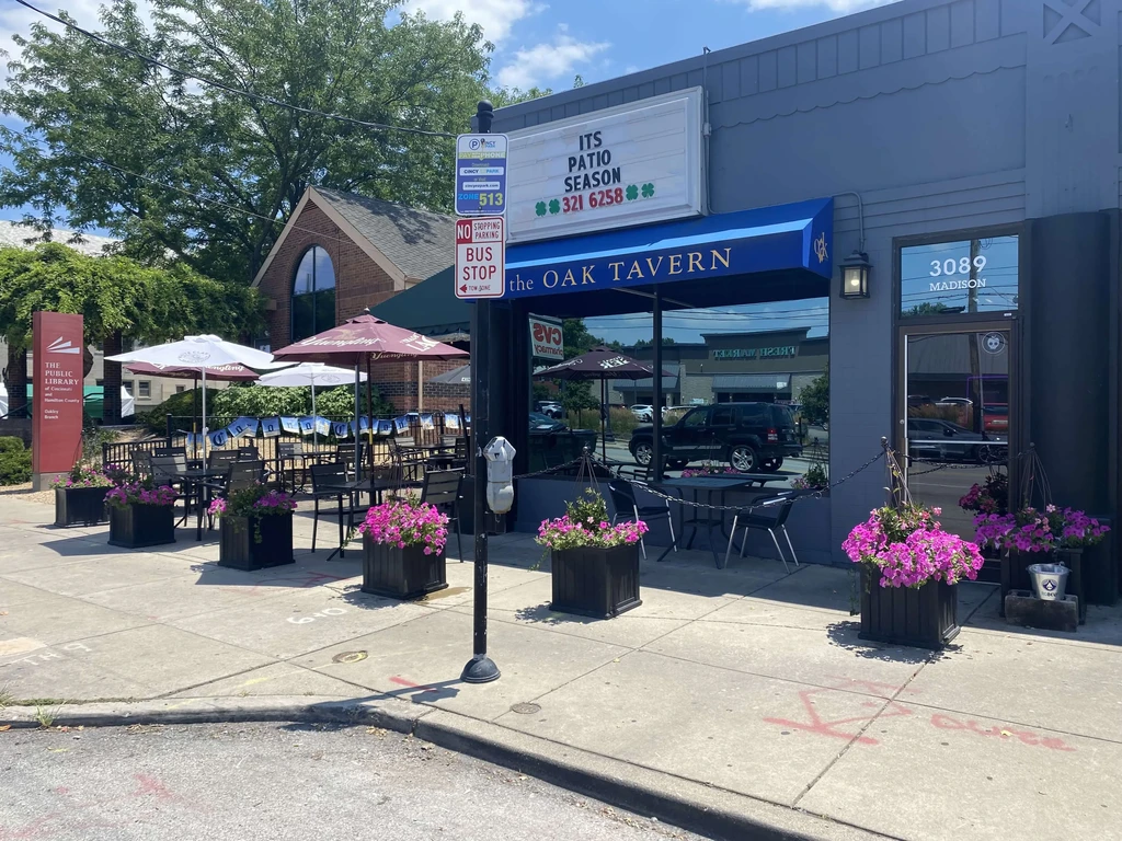 The Oak Tavern exterior with a sunny patio and pink flowers.