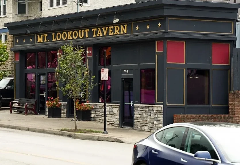 Facade of Mt. Lookout Tavern, dark with gold trim and stone base.