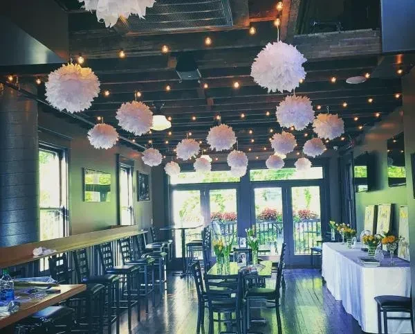 Warm rustic restaurant interior with suspended lanterns and floral decorations.