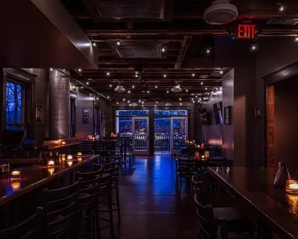 Dimly lit, rustic restaurant interior with string lights, bar counters, and patio.