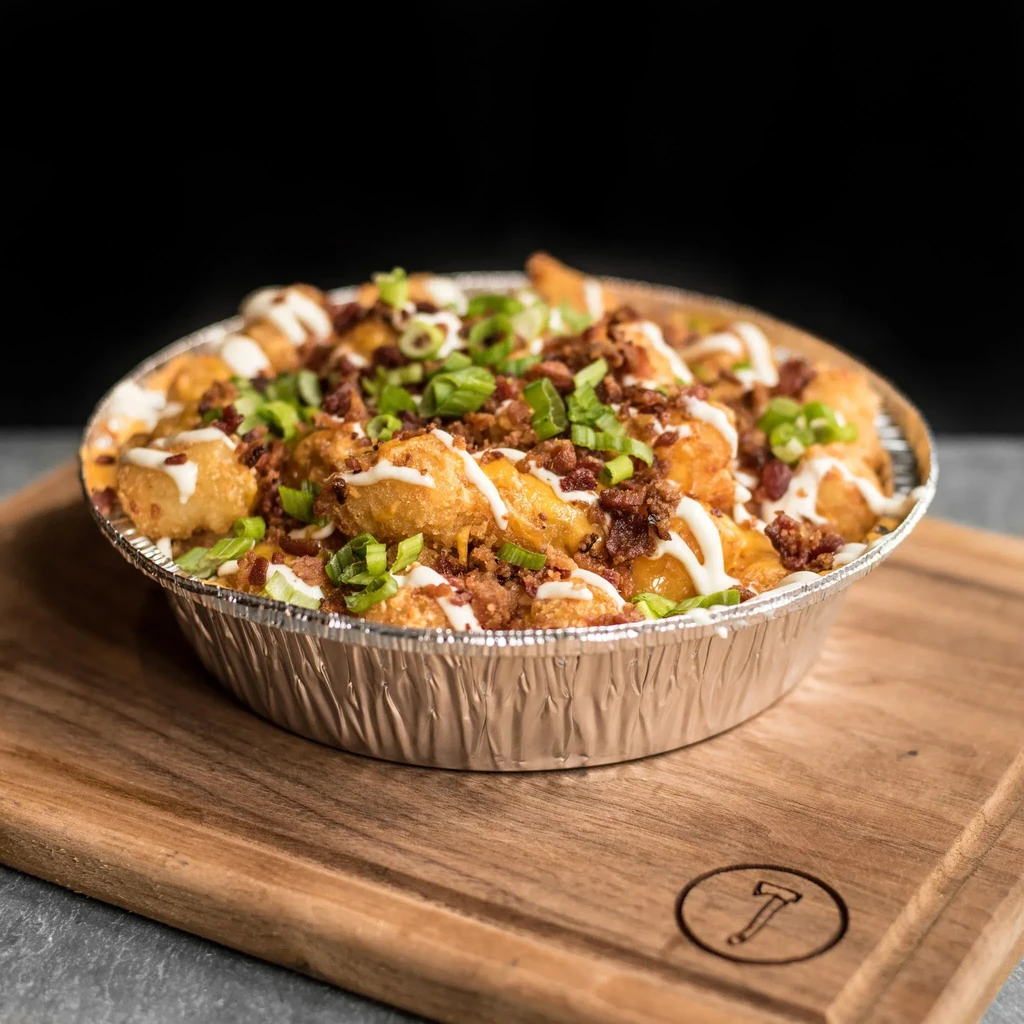 Tater tots topped with cheese, bacon, green onions, and white sauce.