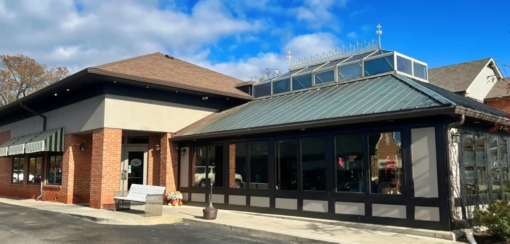 Exterior of a restaurant with mixed roofs, stucco, brick, and glass solarium.