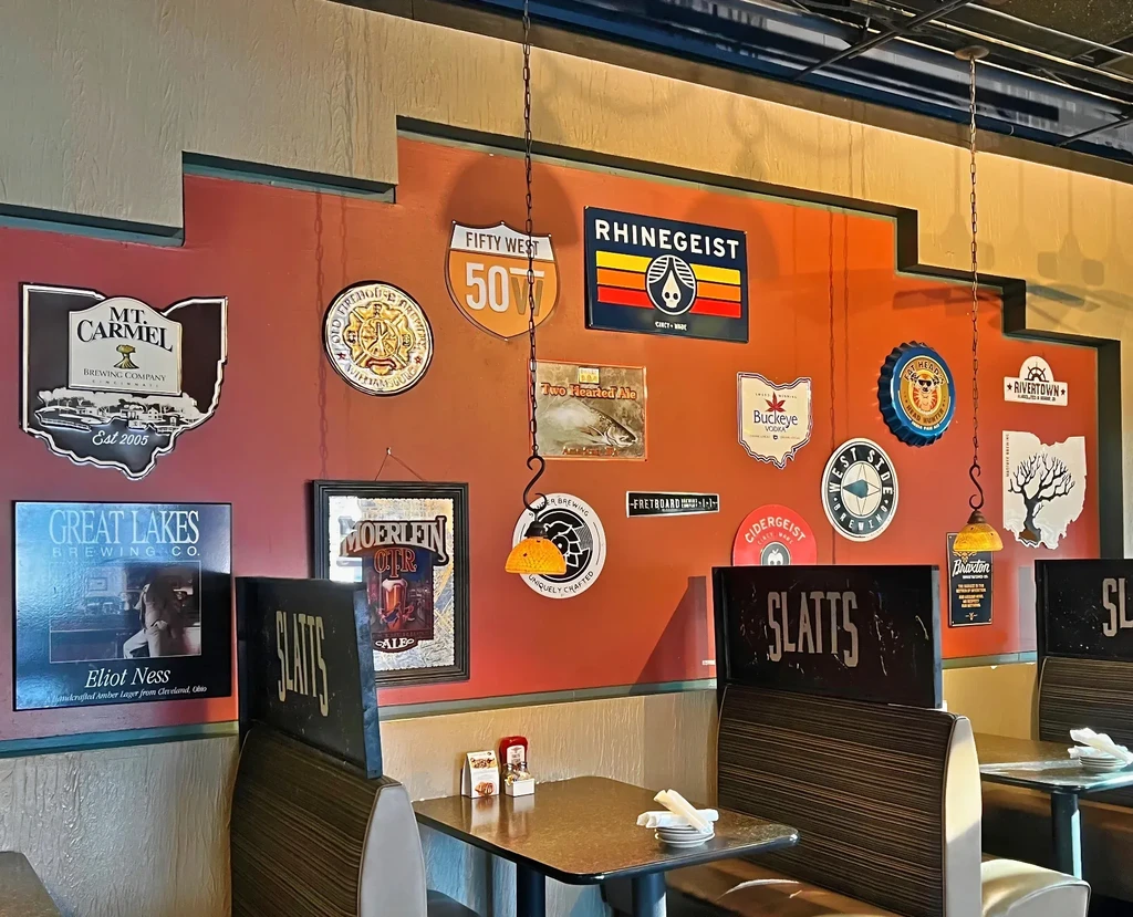 Reddish-brown wall with beverage signs, amber lamps, and striped restaurant booths.