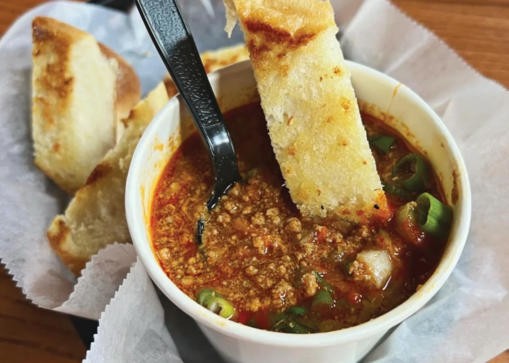 Hearty chili with ground meat, vegetables, and golden toasted bread.