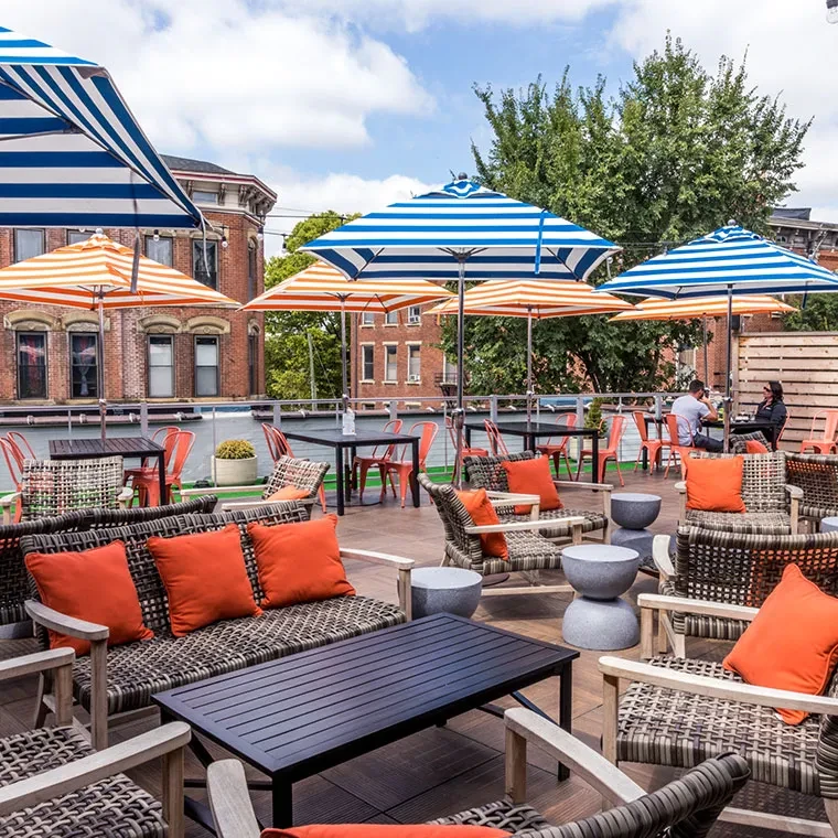 Bright rooftop patio with orange and striped seating, city background.