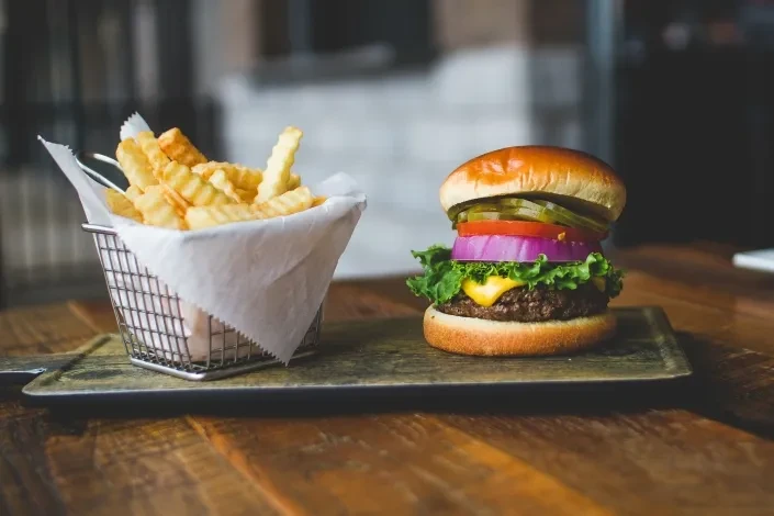 Classic burger and crinkle-cut fries on a wooden table.