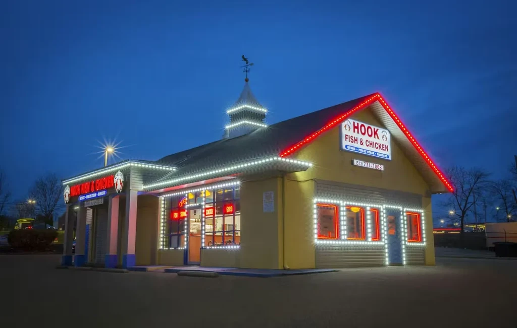 Hook Fish & Chicken restaurant extensively lit with string lights at night.