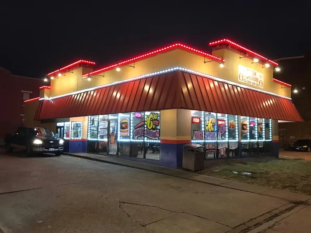 Brightly lit Hook & Cook restaurant at night with red and white lights.