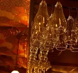 Rack of clear wine glasses hanging upside down in a warm setting.