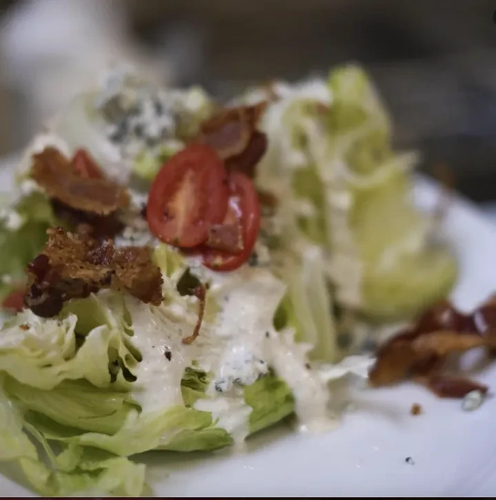 Crisp wedge salad with blue cheese dressing, bacon, and cherry tomatoes.