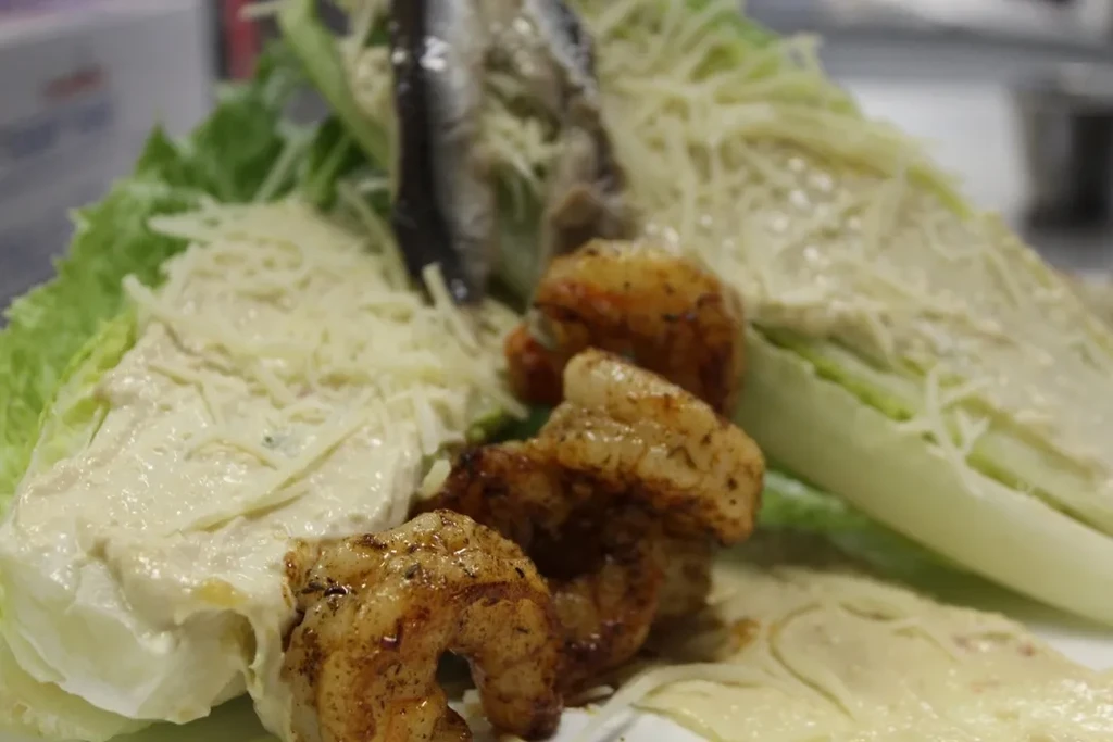 Deconstructed Caesar salad with grilled shrimp, creamy dressing, and cheese.
